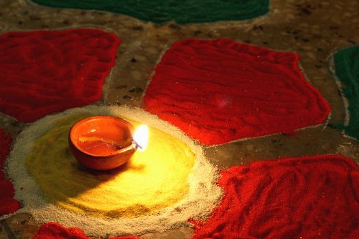 oil lamp at center of colorful rangoli