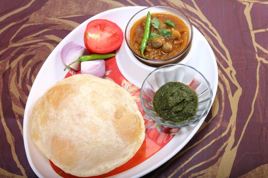 plate of spicy chole bhature, with green chili topping and chutney
indian dish