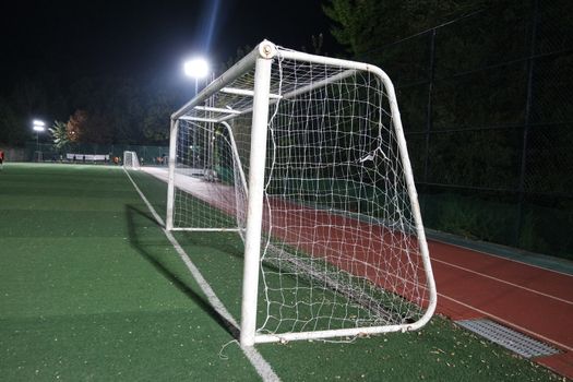 Night view of a soccer goal net under flood lights. Closeup view of goal net in a soccer playground