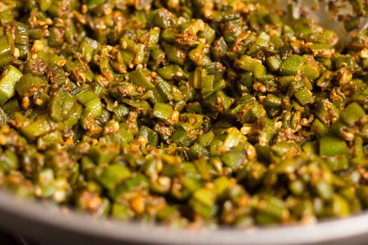 making home made masala bhindi or ladyfinger in karahi using spatula
