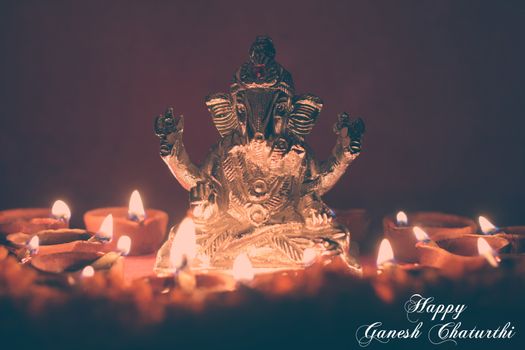 lord ganesha statue, around with oil lamp, retro effect
