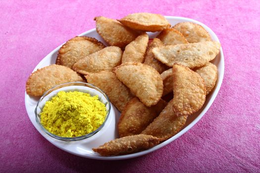 gujia, indian traditional snacks for holi festival with yellow color in bowl