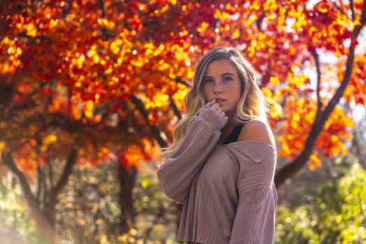 A gorgeous blonde model enjoys a Autumn day outdoors in a park