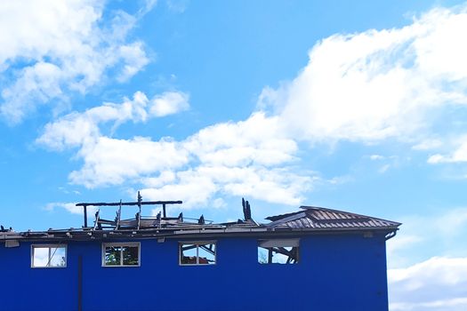 modern frame house with broken roof against cloudy sky background.