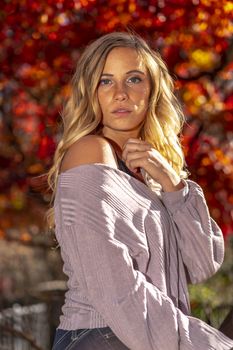 A gorgeous blonde model enjoys a Autumn day outdoors in a park