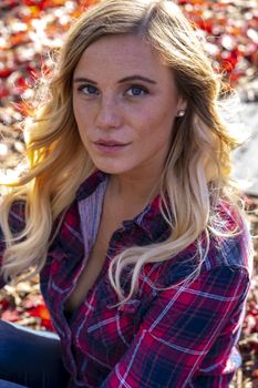 A gorgeous blonde model enjoys a Autumn day outdoors in a park