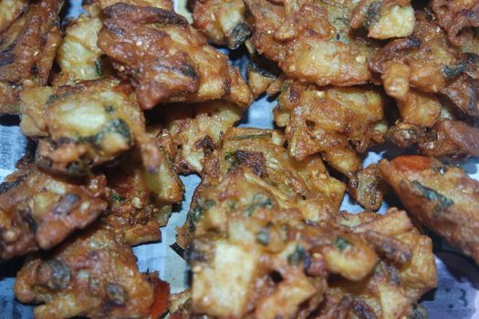 close-up view with selective focus of crispy basin pakora/pakoda or patties are popular indian or pakistani street food snack, served with green salad and sauce. Selective focus of
