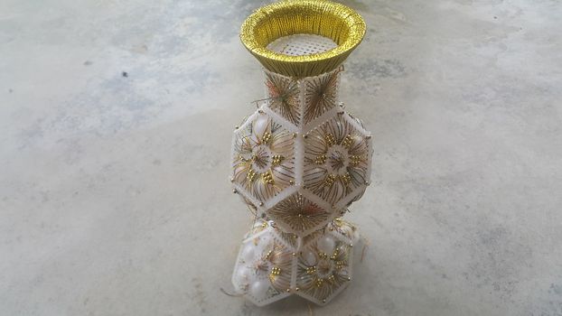 A beautiful ceramic vase placed on a grey floor. The ceramic vase has lovely designs and is used for flowers or bouquet