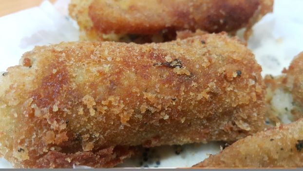 Closeup perspective view of home made spicy and delicious croquettes served in ceramic plate over wooden floor