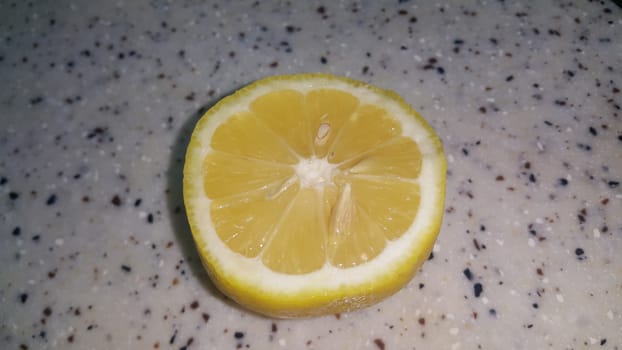 Fresh lemon slices with yellow peelings placed on a grey floor. Top view of fresh juicy lemon slice background