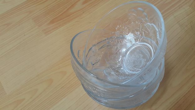 Top view of empty white glass bowls on a wooden floor. Glass bowl with flowers made on its wall