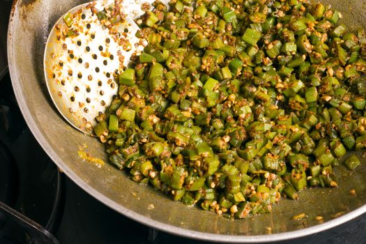 making home made masala bhindi or ladyfinger in karahi using spatula