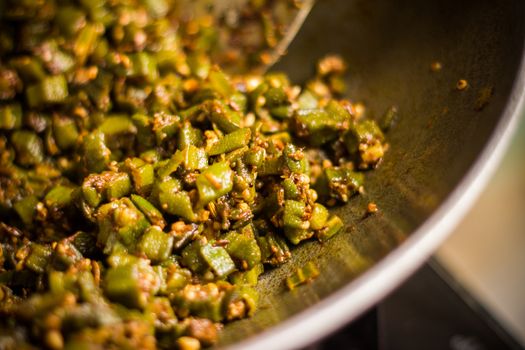 making home made masala bhindi or ladyfinger in karahi using spatula