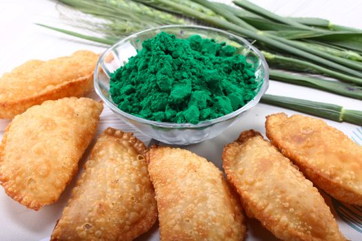 gujia, indian traditional snacks for holi festival with green color in bowl