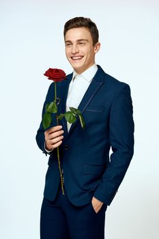 A man in a suit with a rose in his hands a gift date light background. High quality photo