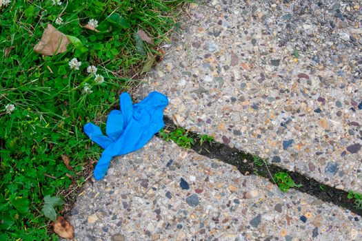 An Old Blue Medical Glove on the Sidewalk for Protection Against COVID-19