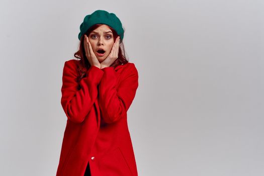 Woman in red coat and in green hat on isolated background cropped model with Copy Space emotions. High quality photo