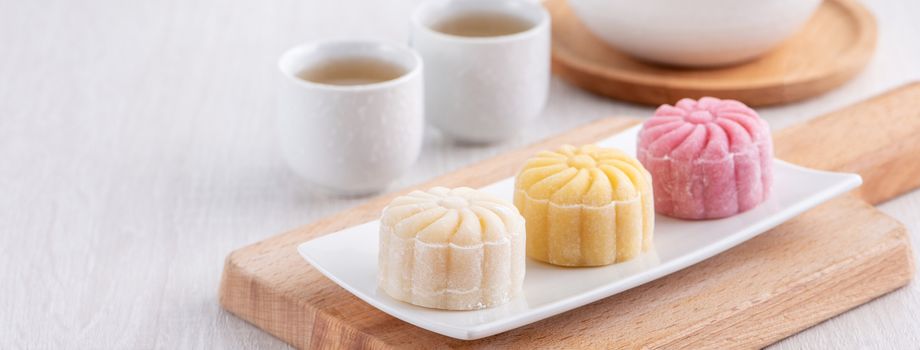 Colorful snow skin moon cake, sweet snowy mooncake, traditional savory dessert for Mid-Autumn Festival on bright wooden background, close up, lifestyle.