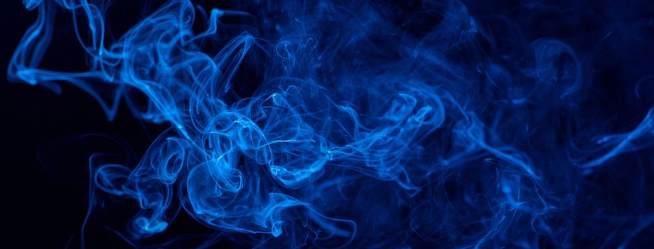 Conceptual image of blue color smoke isolated on dark black background, Halloween design element concept.