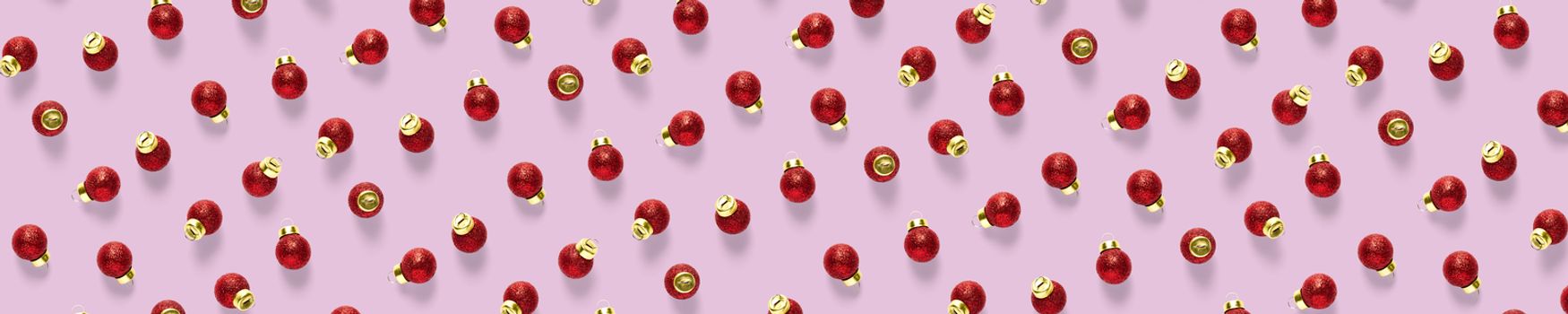 Christmas red decorations on pink background. Christmas ornaments composition for background. Flat lay background madefrome red ornaments decorations