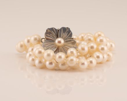 A string of lustrously glowing pearls designed as a necklace with a flower clasp, isolated on a white background