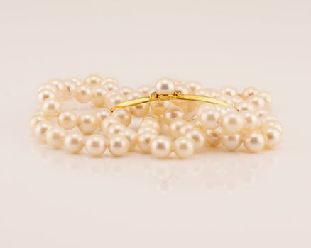 A string of lustrously glowing natural pearls designed as a necklace with a yellow gold bar center feature adorned with a pearl, isolated on a white background