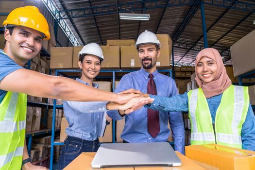 Group of Diversity warehouse worker throwing helmets when success the project and celebrating together in local warehouse, muslim, indian, white caucasian and asian people in export industry concept