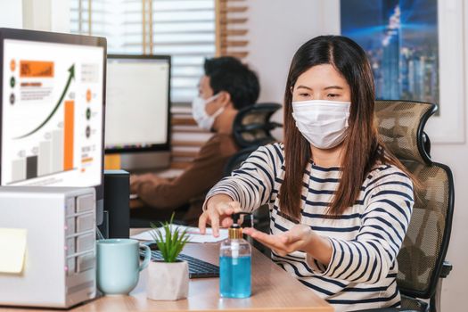 Asian woman worker using hand sanitizer for cleaning her hand when working  with computer in Home office when Covid-19 pandemic, Coronavirus outbreak,education and Social distancing,new normal concept