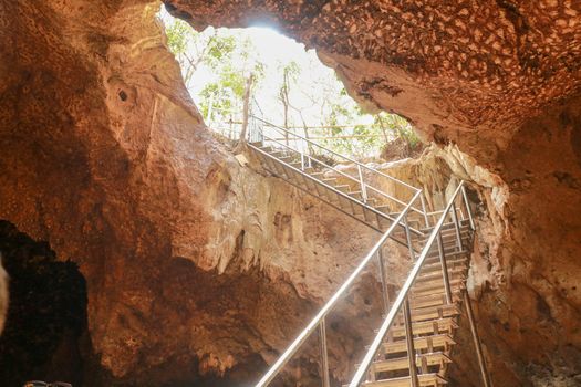 Stainless steel staircase in the cave. Stainless steel staircase to GOA BANGKANG PRABU cave, a bat cave on Lombok island, Indonesia. Bottom view of the blue sky.