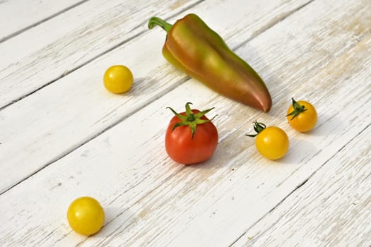 red tomato four yellow tomatoes bell pepper pod on a wooden vintage table