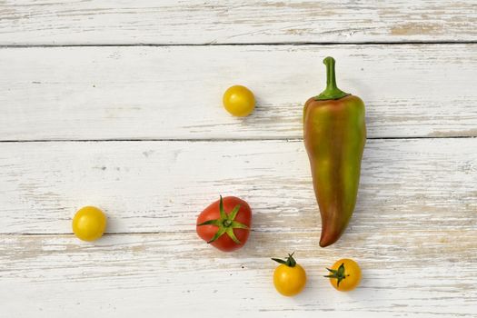 red tomato four yellow tomatoes bell pepper pod on a wooden vintage table, top view