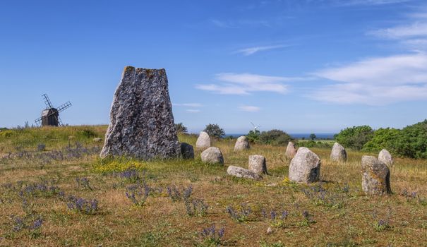 Viking stone ship burial and old windmill in Oland island by beautiful day, Gettlinge, Sweden