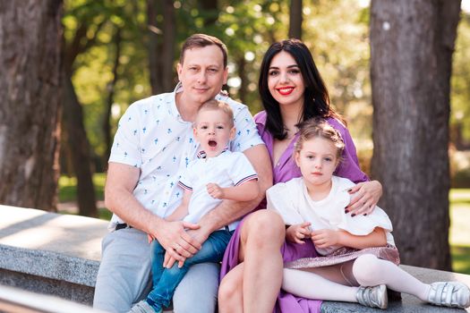 Happy young family with two kids walking in the park. Happy parenting concept