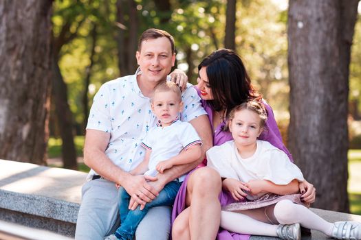 Happy young family with two kids walking in the park. Happy parenting concept