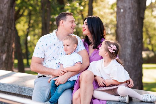 Happy young family with two kids walking in the park. Happy parenting concept