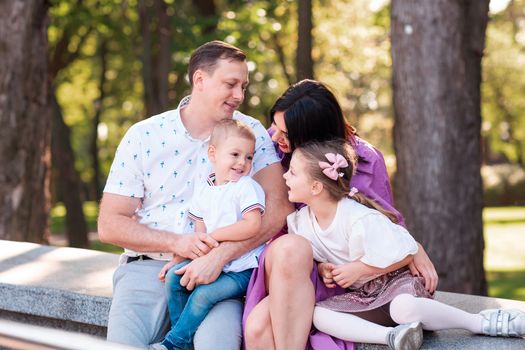 Happy young family with two kids walking in the park. Happy parenting concept