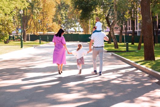 Happy young family with two kids walking in the park. Happy parenting concept