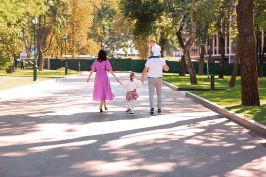 Happy young family with two kids walking in the park. Happy parenting concept