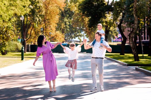 Happy young family with two kids walking in the park. Happy parenting concept