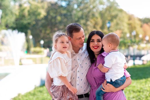 Happy young family with two kids walking in the park. Happy parenting concept