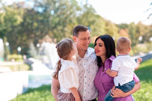 Happy young family with two kids walking in the park. Happy parenting concept