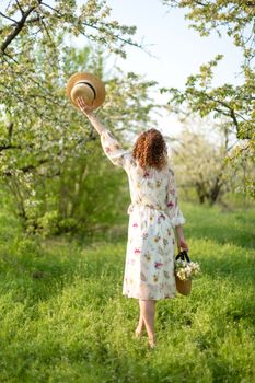 A gorgeous girl walks in a flowering spring garden. The concept of unity of man with nature.