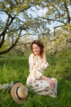 A gorgeous girl walks in a flowering spring garden. The concept of unity of man with nature.