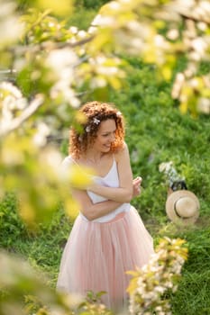 Young attractive girl walks in spring green park enjoying flowering nature. Healthy smiling girl spinning on the spring lawn. Allergy without.