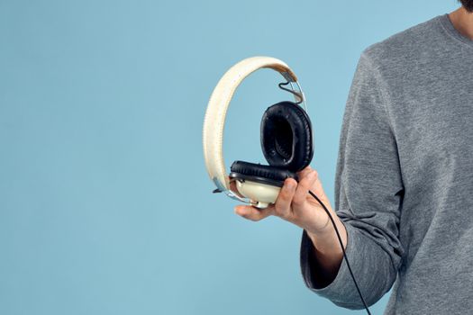 Headphones in man hands cropped view music technology blue background. High quality photo