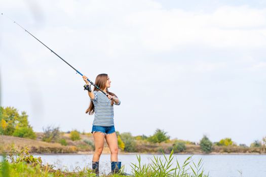 Beautiful young girl fishes on the lake