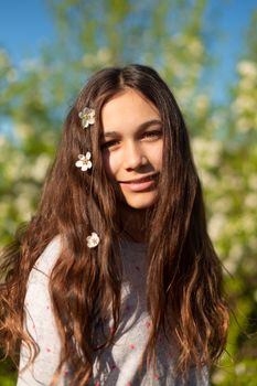 Portrait of a young beautiful teenager girl in a blooming spring green garden.