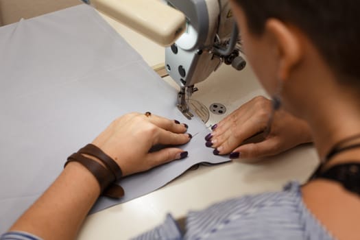Workplace seamstress. Tailoring industry. Girl sews on the sewing machine. Factory clothing.