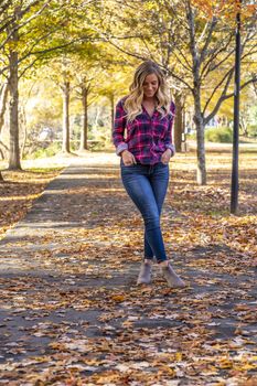 A gorgeous blonde model enjoys a Autumn day outdoors in a park