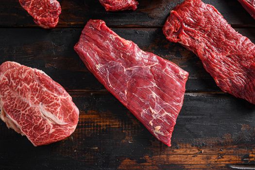 Bio Flank bavette or flap steak beef t steak near tri-tip and top blade oyster cuts close up in front of other cuts in butchery on old wood table top view.